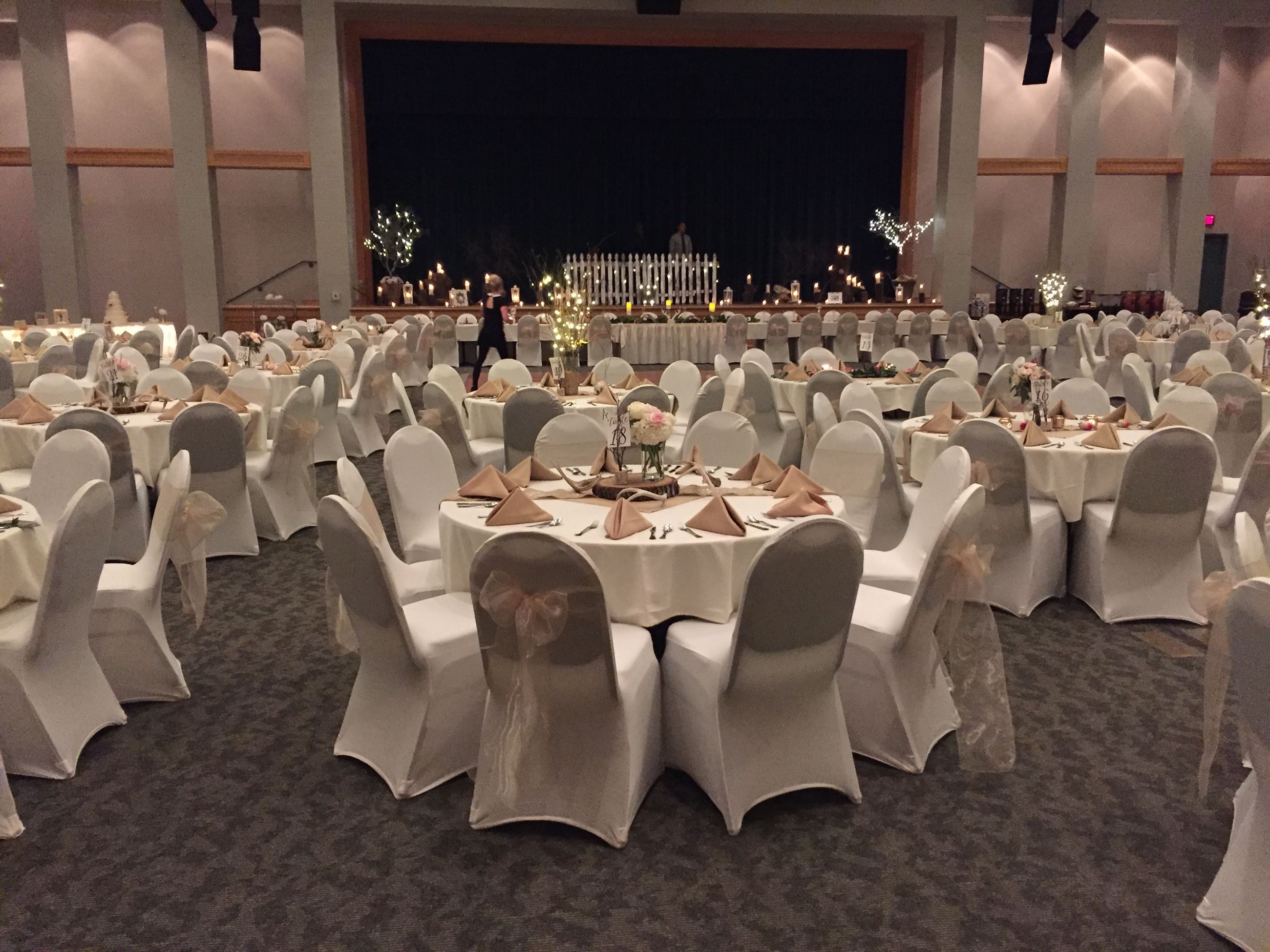 Winter wedding reception with white covered chairs tied with beige tool and napkins